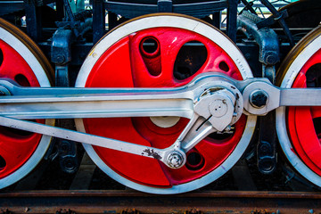 Red driving wheels of a vintage steam engine locomotive. Driving rods, drives, cranks and other...