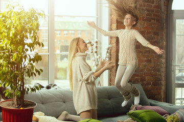 Jumping high. Happy loving family. Mother and daughter spending time together at home. Watching cinema, using laptop, laughting. Mother's day, celebration, weekend, holiday childhood concept.