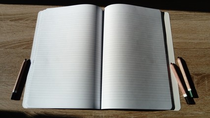 U-turn notebook with blank white pages. To the left and right of the notebook on the wooden table...