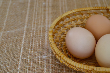 Eggs and chicken eggs. Chicken eggs with feathers, on the cloth of sacking in a wicker basket. Agricultural products, natural eggs. Healthy eating concept.