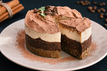 Tiramisu on a beige plate. Coffee with cinnamon. Raw dessert