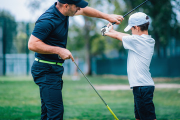 Golf – Personal Training. Golf Instructor Teaching Young Boy How to Play Golf.