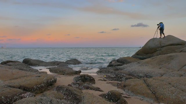 Photographer finds the location for taking nature landscape photo on the beach rock with evening colorful sky 