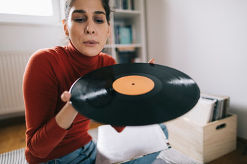 Young woman blowing dust form vinyl record