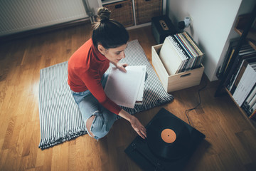 Girl sitting on floor enjoy playing vinyl records on turntable