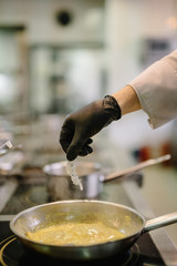 Chef of the restaurant put shrimp on frying pan with raviolli pasta in curry sauce. Smooth image with shallow depth of field.