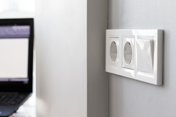 Group of white european electrical outlets and a switch located on a gray wall in a bright modern...