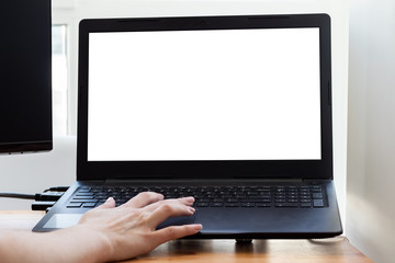 Black laptop with a white mockup screen at the home workplace in a modern bright room near the window and a female hand near the keyboard and touchpad. Freelance, work from home