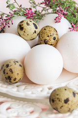 Mix of quail eggs and hen eggs on white vintage plate