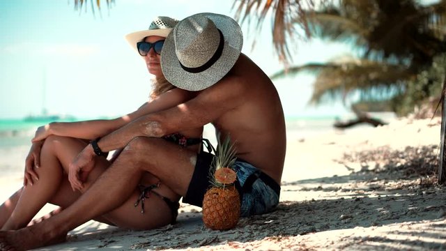 Beautiful Couple Sitting Together On Tropical Beach.Attractive Lovers Vacation Travel At Sea.Happy Romantic Couple Enjoying Relaxing Ocean On Caribbean Resort.Honeymoon Holidays On Maldives Or Bahamas