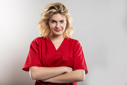 Portrait of nurse wearing red scrub standing with arms crossed