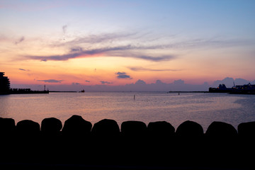 The sun sets over the harbor area in Malmö, Sweden, on a warm August evening. The sky is purple and orange, giving a calm impression.