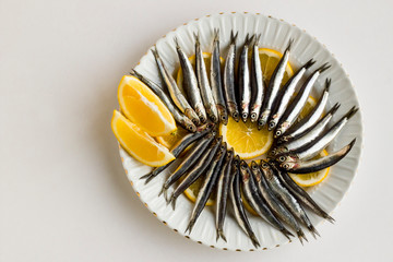 Uncooked,small fish anchovies (Hamsi) designed in round plate on lemon.Top view with copy space