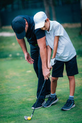 Obraz premium Golf – Personal Training. Golf Instructor Teaching Young Boy How to Play Golf.