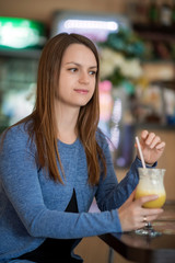 Portrait of a beautiful girl with a cocktail in a cafe.