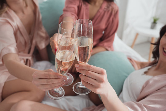 Cropped view of multiethnic friends clinking with champagne glasses at bachelorette party