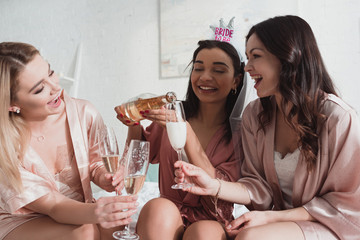 African american bride pouring champagne in glasses with friends at bachelorette party
