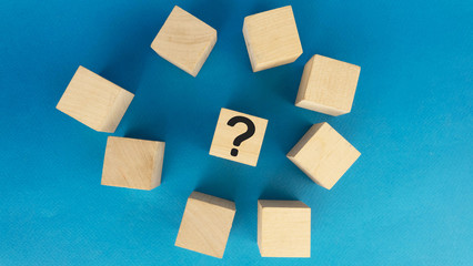 pile of wooden cubes and one with a black question mark on a blue background