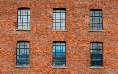 Fototapeta premium Facade / front of an old factory building made of red brick with a lot of vintage windows
