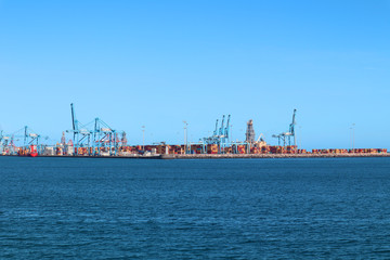 Commercial harbour with cranes, container for imports and exports in a beautiful day