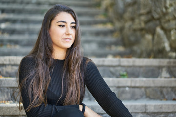 Fototapeta premium Portrait of a young woman sitting on an urban stone staircase
