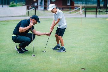 Learning Golf. Boy practicing putting with instructor
