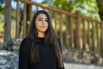 Portrait of a young woman dressed in a sweater and black trousers and in the background you can see the handrail of some stairs.