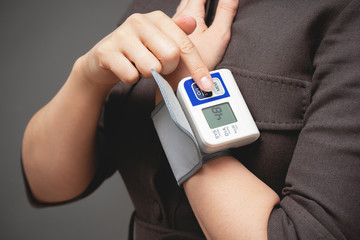 Woman is checking her blood pressure by a wrist tonometer close up.