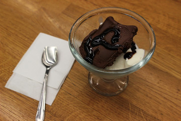 Chocolate and vanilla ice cream in glass bowl on wooden table with white napkin and spoon