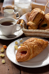 A variety of puff pastry buns with cherries, kiwi, apricot. Rolls, croissants with various fillings. A Cup of coffee with milk, Breakfast. Still-life.
