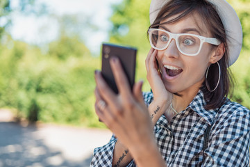 Surprised young woman holding and looking to their smartphone