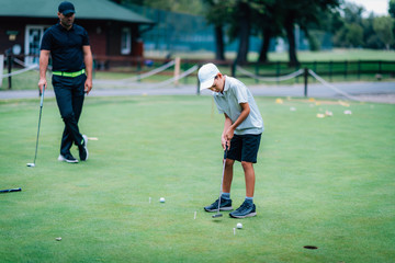 Learning Golf. Boy practicing putting with instructor
