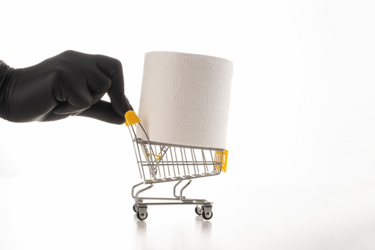 Consumer buying panic about coronavirus covid-19 concept. Toilet paper roll in shopping trolley.A black gloved hand is driving trolley for hygiene.People are stocking up essentials for home quarantine