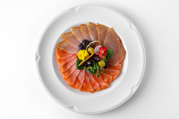 Plate with appetizer of fish and seafood. Sliced salted fish fillet. Smoked salmon, tuna, perch. Banquet festive dishes. Gourmet restaurant menu. White background.