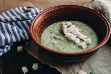 Green cream vegetable soup broccoli, peas, zucchini, spinach with croutons. Delicious vegetarian healthy food.