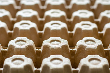 A lot of empty cardboard egg cartons in a row. Bottom of egg trays.