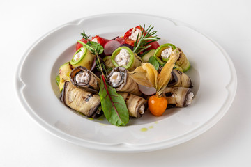 Appetizer of grilled vegetables from zucchini, eggplants, tomatoes, sweet peppers, onions. Rolls stuffed with cheese. Banquet festive dishes. Gourmet restaurant menu. White background.