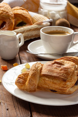 A variety of puff pastry buns with cherries, kiwi, apricot. Rolls, croissants with various fillings. A Cup of coffee with milk, Breakfast. Still-life.