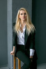 vertical portrait of a beautiful young blonde against a gray wall