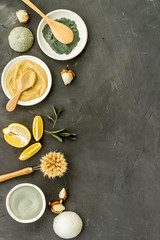 Natural spa concept with various cosmetic clays. Composition with healing herbs, wooden massage brush on gray table, flat lay, space for text
