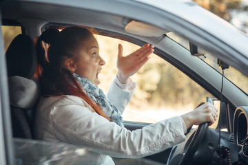 Middle aged woman sits in the car and complains on traffic situation - car stands on the verge of...