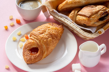 A variety of puff pastry buns with cherries, kiwi, apricot. Rolls, croissants with various fillings. A Cup of coffee with milk, Breakfast. Still-life.