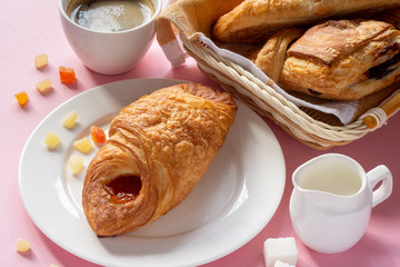 A variety of puff pastry buns with cherries, kiwi, apricot. Rolls, croissants with various fillings. A Cup of coffee with milk, Breakfast. Still-life.