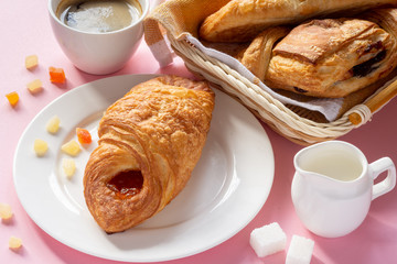 A variety of puff pastry buns with cherries, kiwi, apricot. Rolls, croissants with various fillings. A Cup of coffee with milk, Breakfast. Still-life.