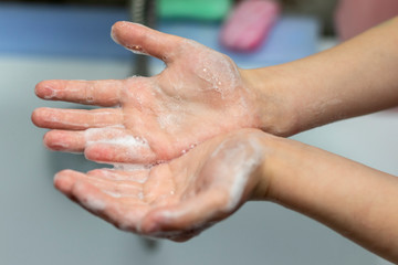 Fototapeta premium A child washes his hands in front of a faucet with water in the bathroom. Close-up