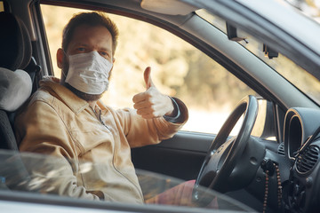 a man driving a car puts on a medical mask during an epidemic, a taxi driver in a mask, protection from the virus