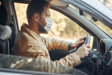 a man driving a car puts on a medical mask during an epidemic, a taxi driver in a mask, protection...