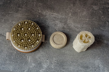 eco brush, solid shampoo,luffa on grey background. Flat lay on eco cosmetics.
