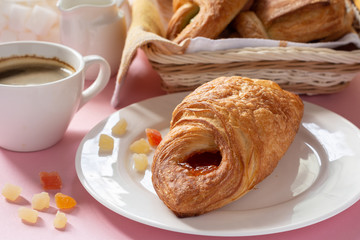 A variety of puff pastry buns with cherries, kiwi, apricot. Rolls, croissants with various fillings. A Cup of coffee with milk, Breakfast. Still-life.