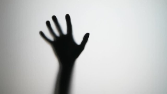 Male hand move from blur and hit glass, horror style shot. Someone wants to go through thick glass wall, flap and smash arm on hard barrier. Black silhouette with white background